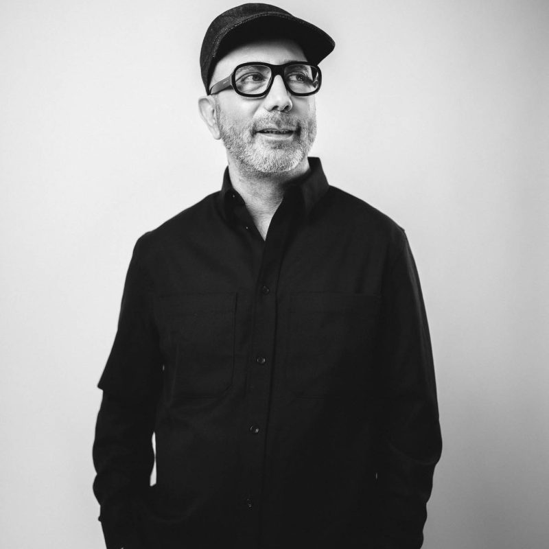 Schwarzweiß Portrait eines Berliner Designers Emamidesign stehend vor weißem Hintergrund